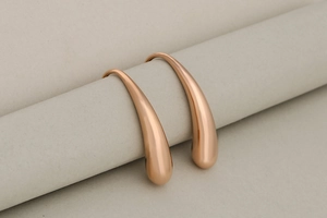 Detail view of rose gold teardrop earrings with a smooth polished mirror finish surface