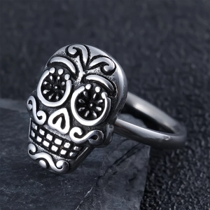 Macro shot of a vintage silver punk skull ring on a textured dark grey stone base