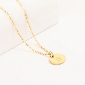 Macro view of golden stainless steel round pendant with letter B on a pearl necklace