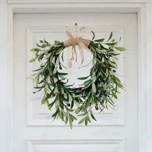 Detailed view of olive wreath with green leaves and a linen bow on a white door