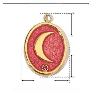 Macro detail of 17mm gold stainless steel oval pendant with red enamel and moon charm