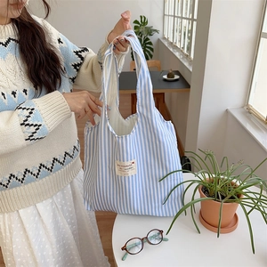Close-up of blue and white striped canvas tote bag with a minimalist woven label