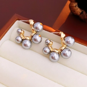 Gros plan d'élégantes boucles d'oreilles en perles grises avec base dorée en écrin