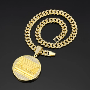 Gold-plated Cuban chain necklace with iced out Last Supper medallion on black reflective background