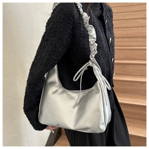 Detail of silver hobo shoulder bag with pleated strap and decorative bow accent