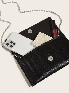 Internal storage detail of black textured clutch with phone and cosmetics