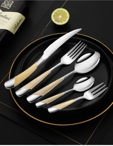 Detail of 5-piece gold-tone cutlery set with textured handles on luxury black plate