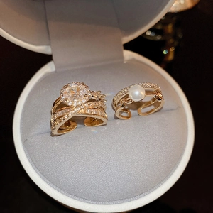 Primo piano di anelli multistrato placcati oro con zircone e perla in scatola grigia