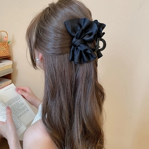 Detail of a large black fabric bow hair claw clip worn on a woman's hair for a chic look