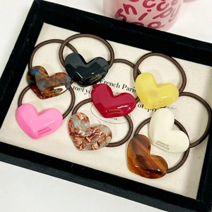 Set of heart-shaped acetate hair ties in various marble and solid colors on black velvet