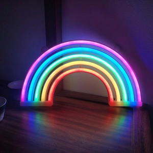Close-up of vibrant rainbow LED neon sign glowing on a wooden surface for home decor