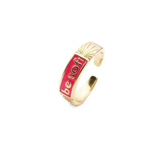 Gold plated ring with red enamel inlay and BE SOFT lettering on white background