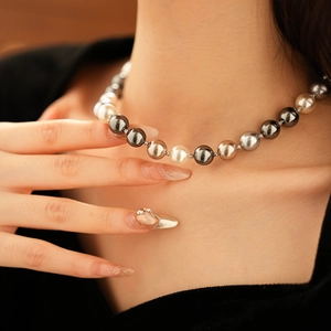 Close-up of elegant pearl necklace with alternating white and grey pearls on a model neck