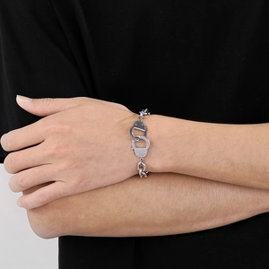 Gros plan d'un bracelet menottes en acier inoxydable poli argenté au poignet d'un homme