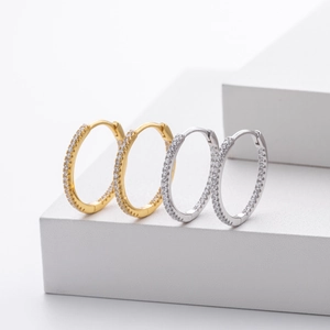 Détail de créoles en argent et or avec pavé de zircons sur supports géométriques