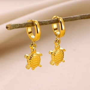 Gros plan de boucles d'oreilles tortue dorées sur une branche avec ombres naturelles