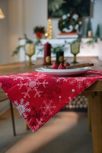 Detail of red Christmas placemat with white snowflake patterns on a wooden dining table
