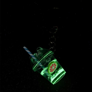 Luminous fruit tea cup keychain glowing in the dark with green liquid and lemon slice
