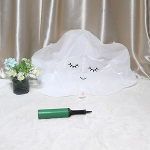 Detail of white cloud foil balloon with smiling face and pump on white carpet decor
