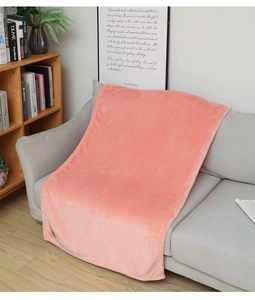 Close-up of soft coral pink flannel blanket with plush texture on a grey sofa