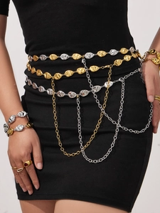 Detail of layered gold and silver mixed metal waist chains and jewelry on model