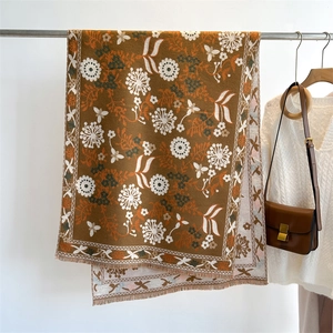 Brown cashmere-feel scarf with vintage floral patterns and fringe on a metal hanger