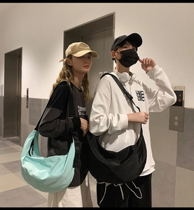 Models wearing oversized nylon crossbody dumpling bags in light blue and black colors