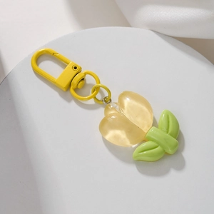 Close-up of a handmade yellow tulip keychain with green leaves and a metal spring clip