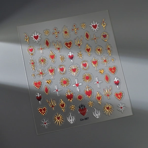 Detail of gold and red heart cross nail art stickers with metallic finish on a grey surface