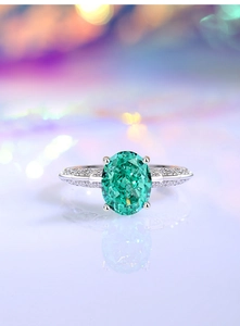 Macro shot of silver ring featuring oval green gemstone and pavé white diamonds