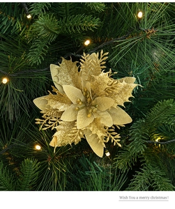 Macro view of gold sequined poinsettia ornament on Christmas tree with warm lights