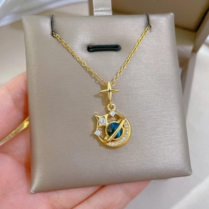 Macro detail of gold celestial necklace with blue sphere and sparkling moon pendant