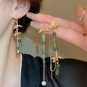 Close-up of golden bamboo tassel earring with green faux jade and white pearl on model