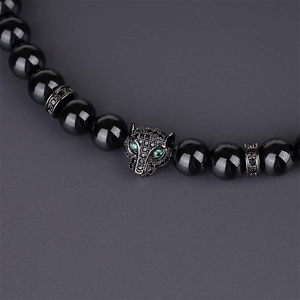 Close-up of leopard head charm with green zircon eyes on black malachite beaded bracelet