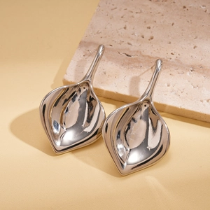 Détail de boucles d'oreilles argentées en forme de feuille au fini métallique poli sur pierre