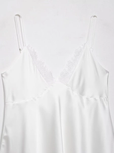 Détail d'une robe en satin blanc avec dentelle au décolleté en V et fines bretelles