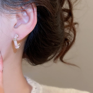 Close-up of pink enamel bamboo C-shape earrings with gold trim and zircon on ear