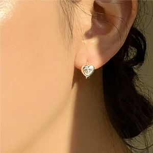 Close-up of minimalist heart-shaped silver stud earring featuring a clear cubic zirconia