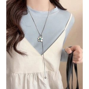 Elegant silver flower pendant necklace with a green gemstone on a model's neck