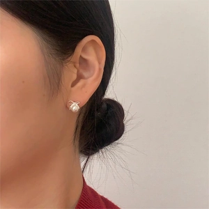 Detail of silver bow pearl earrings shown on a model for an elegant and refined look