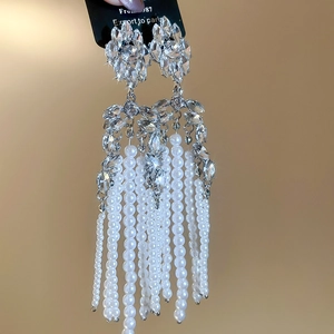 Close-up of sparkling floral rhinestone earrings with long white pearl tassels