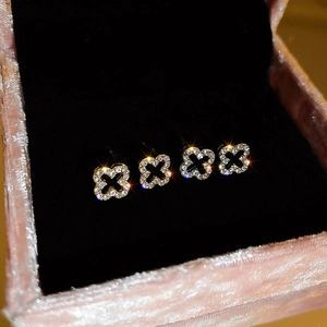 Diamond-studded hollow four-leaf flower stud earrings displayed in a pink velvet jewelry box