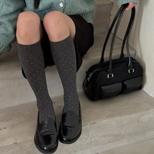 Détail de chaussettes hautes en laine gris foncé à pois blancs et mocassins