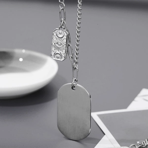 Détail du collier en titane argenté avec relief lune et étoile et plaque ovale lisse