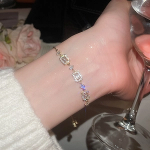 Detail view of gold-plated bracelet with rectangular zircons on wrist with adjustable chain