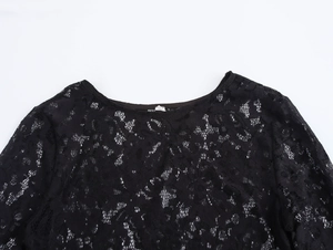 Detail view of the intricate floral lace pattern and round neckline on a black lace dress