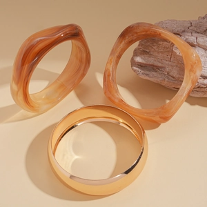 Three-piece set of amber marble acrylic resin bangles with a wide gold metal cuff bracelet