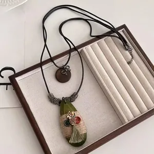 Detail of long ethnic necklace with wooden pendants and green silk tassel on tray