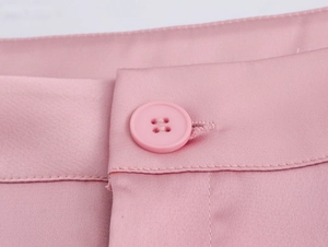 Gros plan détaillé d'un pantalon rose avec bouton à quatre trous assorti et coutures fines