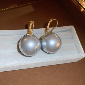 Vue détaillée de grandes perles gris-argent avec crochets dorés sur un plateau en velours